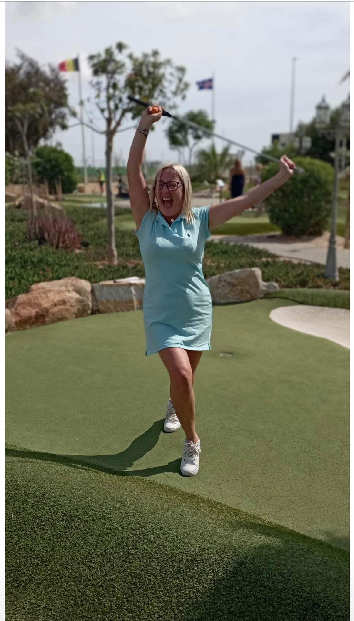 A player celebrating a hole with her putter raised on the adventure golf course