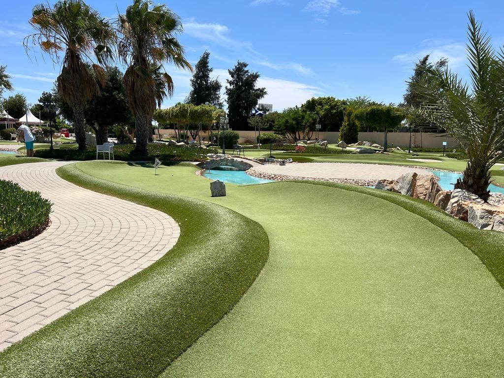 Curving artificial grass fairways, palm trees and water at Golf Delux